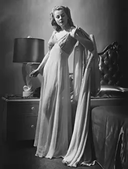 House Interior Prints: Young woman standing by bed wearing dressing gown, (B&W)