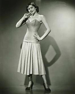 Corsetry Gallery: Young woman standing in studio, smiling, (B&W)