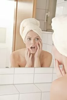 Young woman with a towel wrapped around her head in front of a mirror