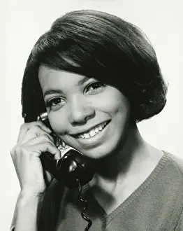 On The Phone Prints: Young woman using phone in studio, smiling, (B&W), portrait