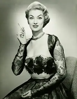 Model Prints: Young woman wearing evening dress smoking cigarette, (B&W), portrait