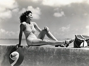 Swimming Gallery: Young woman wearing knitted swimsuit, posing on wall by ocean. (Photo by H)