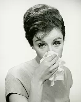Young woman wiping nose with handkerchief, posing in studio, (B&W), (Portrait)