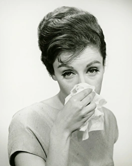 Young woman wiping nose with handkerchief, posing in studio, (B&W), (Portrait) Young woman wiping nose with handkerchief, posing in studio, (B&W), (Portrait)