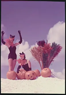 Young Women in Costume Posing on Beach with Pumpkins