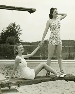 Two young women holding hands on springboard, (B&W)