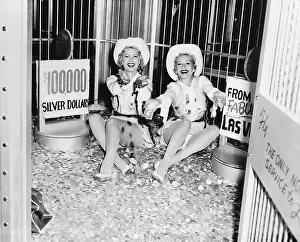 Us Dollars Prints: Young Women Sitting Near Poster Signs Promoting Gambling
